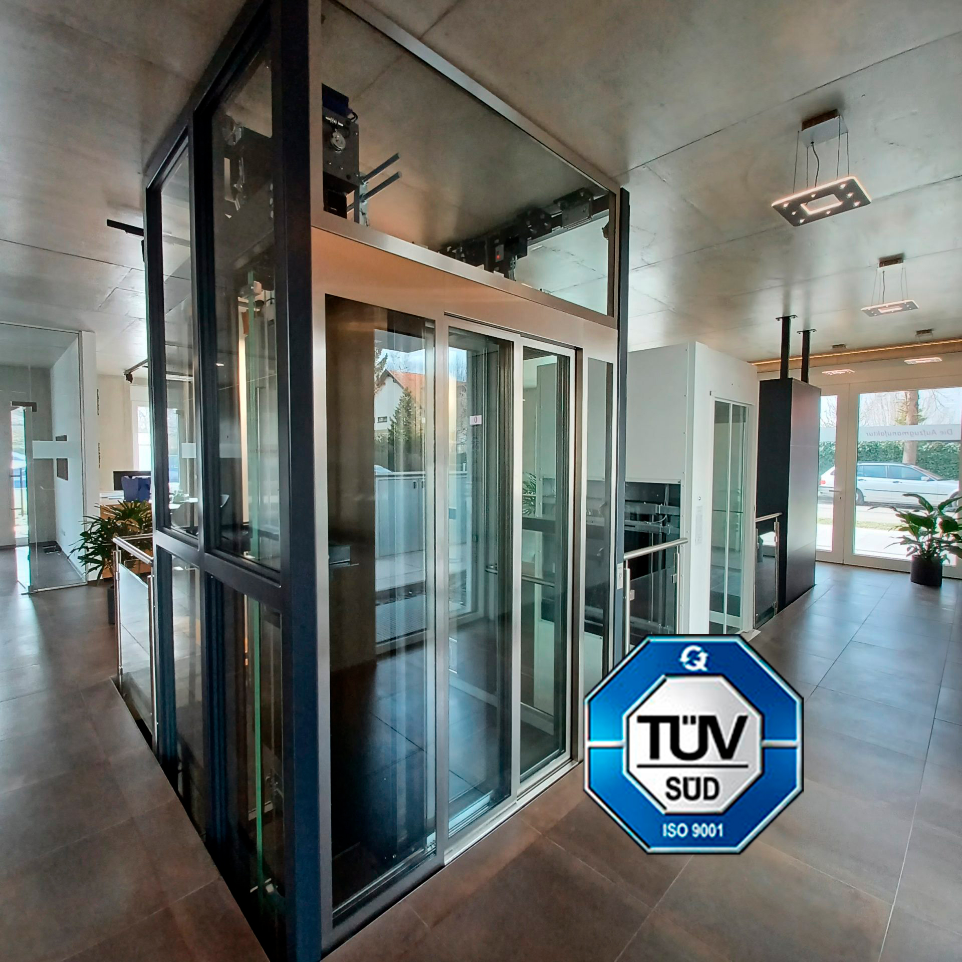 Moderne Aufzüge im Showroom mit TÜV SÜD ISO 9001 Logo
