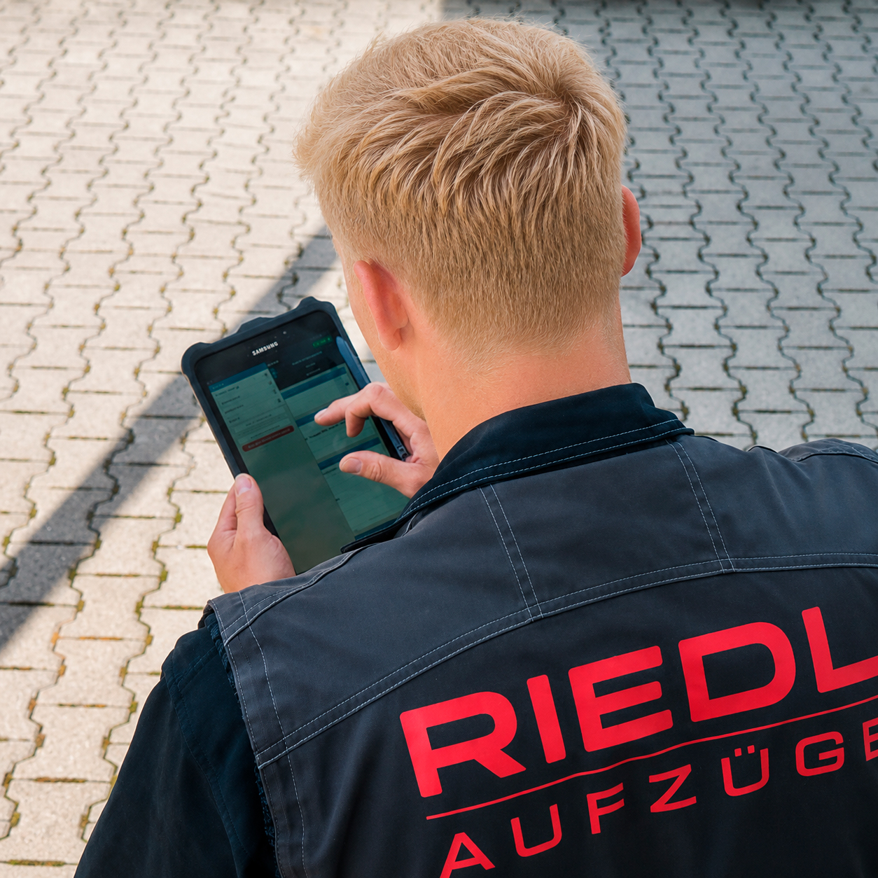 Über die Schulter eines Mitarbeiters sieht man, wie er ein Computer-Tablet bedient.